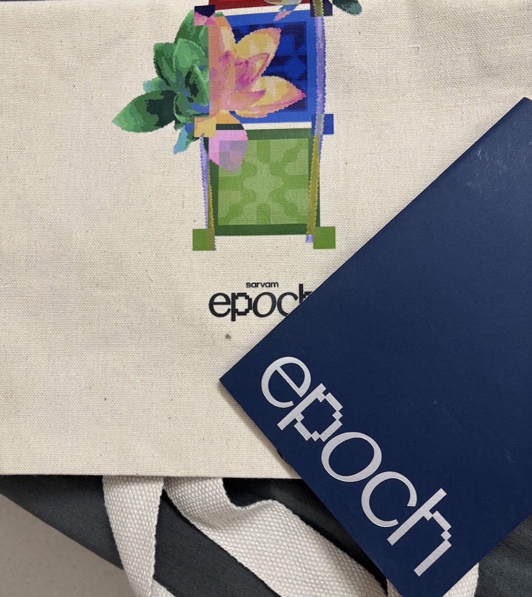 Canvas Sarvam Epoch tote bag with a pixel-art floral print, and an epoch booklet